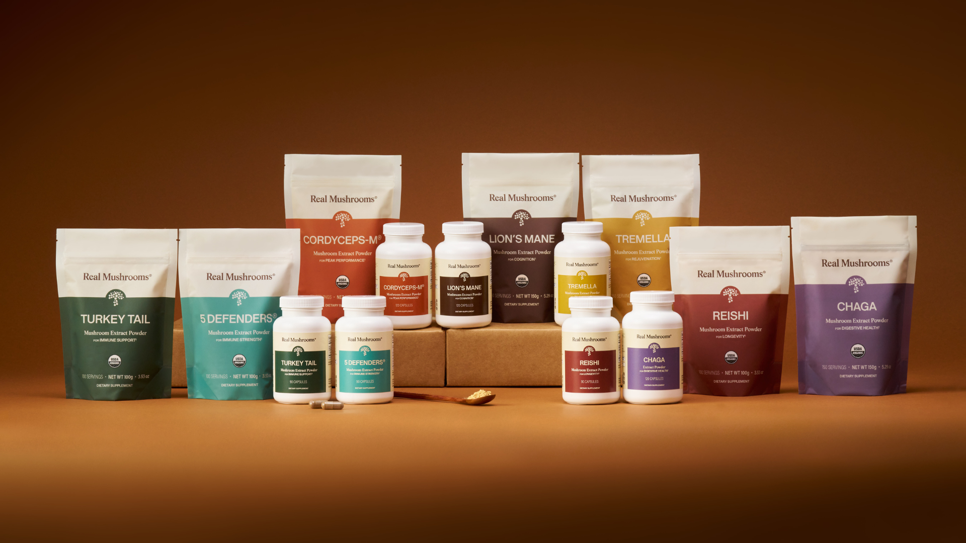 A variety of Real Mushrooms branded supplement powders and capsules featuring healthy mushrooms are displayed on a brown surface with a brown background.