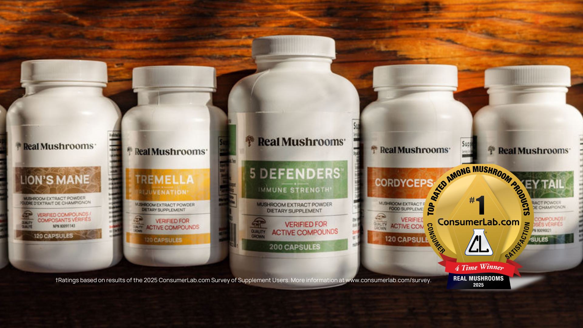 Five bottles of Real Mushrooms supplements are arranged on a wooden surface, with a ConsumerLab Awards badge proudly displayed on the front right bottle, highlighting this trusted mushroom supplement brand.